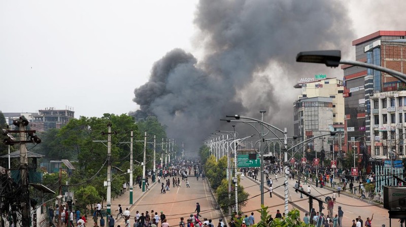 Para demonstran bereaksi di dekat asap yang mengepul dari kompleks Parlemen menyusul kebakaran yang terjadi selama protes terhadap tewasnya 19 orang pada hari Senin setelah protes antikorupsi yang dipicu oleh larangan media sosial, yang kemudian dicabut, selama jam malam di Kathmandu, Nepal, 9 September 2025. (REUTERS/Adnan Abidi)