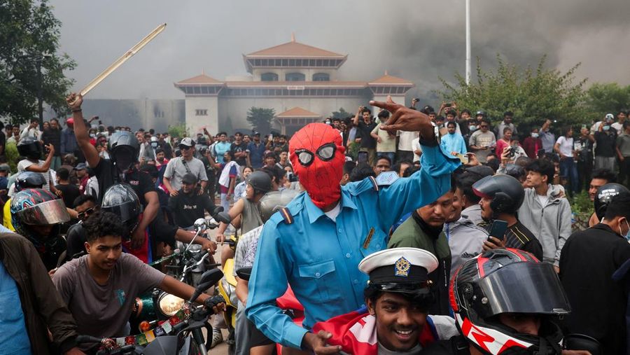Para demonstran bereaksi di dekat asap yang mengepul dari kompleks Parlemen menyusul kebakaran yang terjadi selama protes terhadap tewasnya 19 orang pada hari Senin setelah protes antikorupsi yang dipicu oleh larangan media sosial, yang kemudian dicabut, selama jam malam di Kathmandu, Nepal, 9 September 2025. (REUTERS/Adnan Abidi)