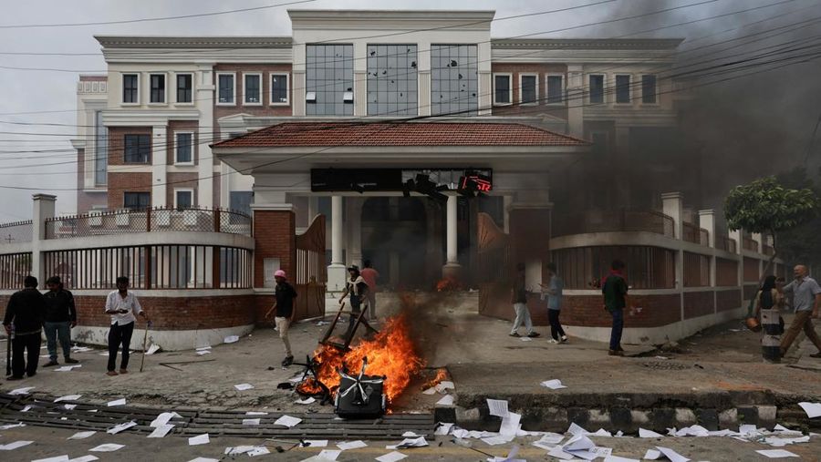 Para demonstran bereaksi di dekat asap yang mengepul dari kompleks Parlemen menyusul kebakaran yang terjadi selama protes terhadap tewasnya 19 orang pada hari Senin setelah protes antikorupsi yang dipicu oleh larangan media sosial, yang kemudian dicabut, selama jam malam di Kathmandu, Nepal, 9 September 2025. (REUTERS/Adnan Abidi)