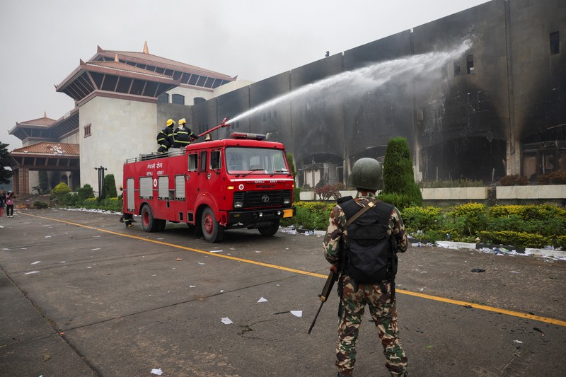 Seorang tentara Nepal berjaga-jaga saat tim tentara mencoba memadamkan api di gedung Parlemen, menyusul tewasnya 19 orang pada hari Senin setelah protes antikorupsi yang dipicu oleh larangan media sosial, yang kemudian dicabut, di Kathmandu, Nepal, 10 September 2025. Seorang tentara Nepal berjaga-jaga saat tim tentara mencoba memadamkan api di gedung Parlemen, menyusul tewasnya 19 orang pada hari Senin setelah protes antikorupsi yang dipicu oleh larangan media sosial, yang kemudian dicabut, di Kathmandu, Nepal, 10 September 2025. (REUTERS/Adnan Abidi)