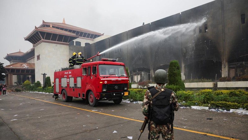 Seorang tentara Nepal berjaga-jaga saat tim tentara mencoba memadamkan api di gedung Parlemen, menyusul tewasnya 19 orang pada hari Senin setelah protes antikorupsi yang dipicu oleh larangan media sosial, yang kemudian dicabut, di Kathmandu, Nepal, 10 September 2025. (REUTERS/Adnan Abidi)