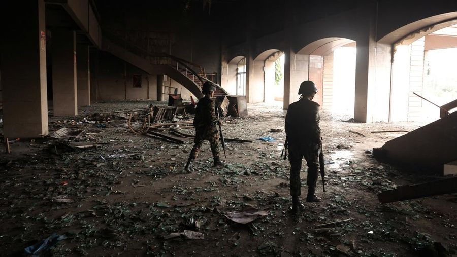 Seorang tentara Nepal berjaga-jaga saat tim tentara mencoba memadamkan api di gedung Parlemen, menyusul tewasnya 19 orang pada hari Senin setelah protes antikorupsi yang dipicu oleh larangan media sosial, yang kemudian dicabut, di Kathmandu, Nepal, 10 September 2025. (REUTERS/Adnan Abidi)