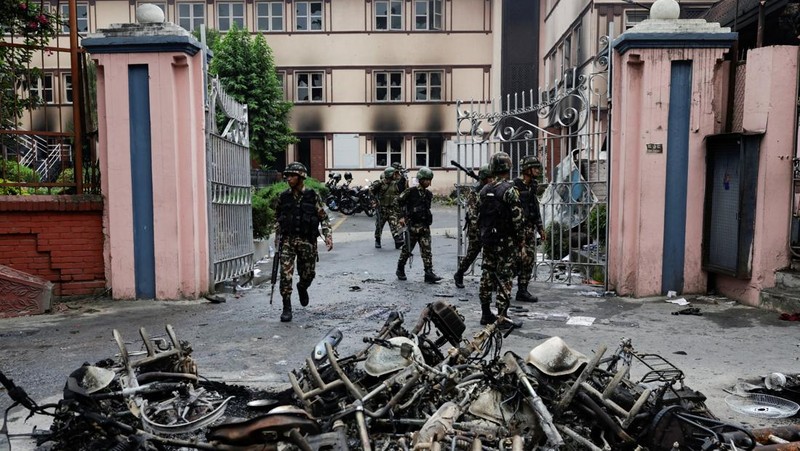 Seorang tentara Nepal berjaga-jaga saat tim tentara mencoba memadamkan api di gedung Parlemen, menyusul tewasnya 19 orang pada hari Senin setelah protes antikorupsi yang dipicu oleh larangan media sosial, yang kemudian dicabut, di Kathmandu, Nepal, 10 September 2025. (REUTERS/Adnan Abidi)