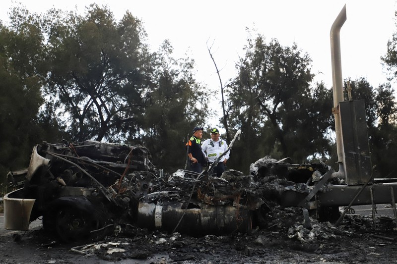 Seorang pria berjalan di samping sisa-sisa hangus sebuah trailer, salah satu kendaraan yang rusak dalam ledakan truk tangki gas di Jalan Ignacio Zaragoza, tempat beberapa orang mengalami luka bakar setelah truk tangki terbalik, di Mexico City, Meksiko, 10 September 2025. (REUTERS/Quetzalli Blanco)