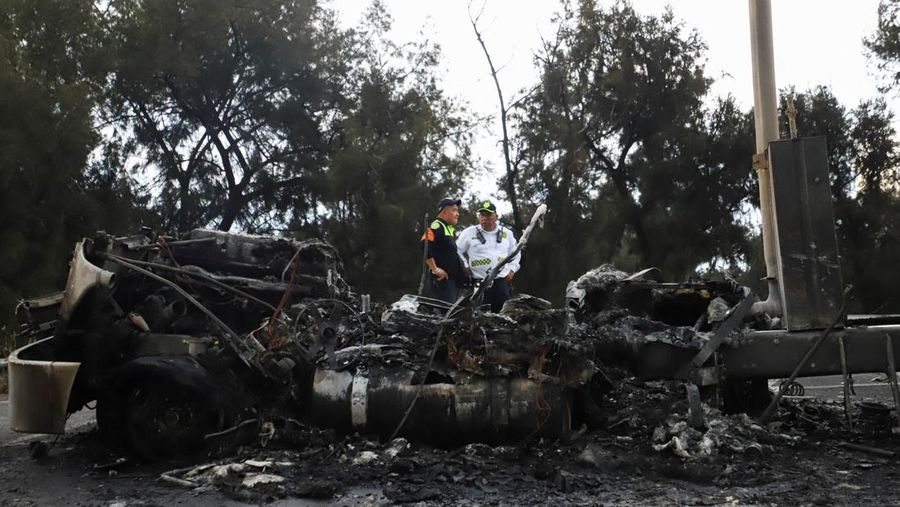 Seorang pria berjalan di samping sisa-sisa hangus sebuah trailer, salah satu kendaraan yang rusak dalam ledakan truk tangki gas di Jalan Ignacio Zaragoza, tempat beberapa orang mengalami luka bakar setelah truk tangki terbalik, di Mexico City, Meksiko, 10 September 2025. (REUTERS/Quetzalli Blanco)