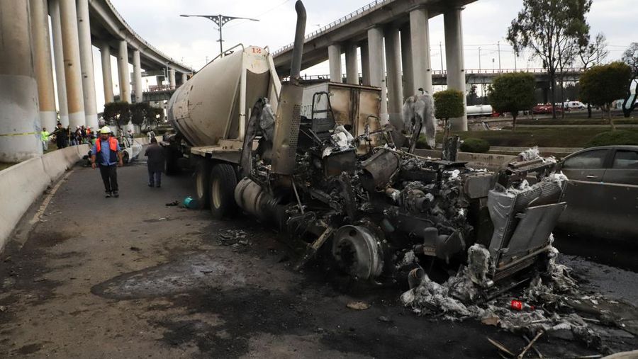 Seorang pria berjalan di samping sisa-sisa hangus sebuah trailer, salah satu kendaraan yang rusak dalam ledakan truk tangki gas di Jalan Ignacio Zaragoza, tempat beberapa orang mengalami luka bakar setelah truk tangki terbalik, di Mexico City, Meksiko, 10 September 2025. (REUTERS/Quetzalli Blanco)