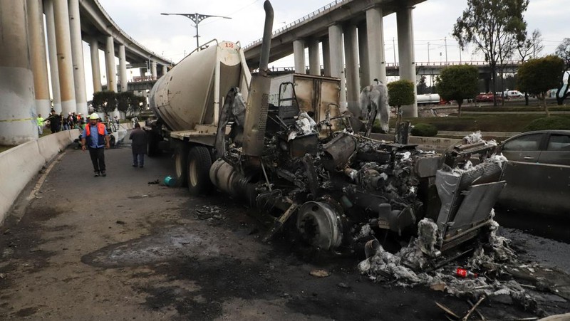 Seorang pria berjalan di samping sisa-sisa hangus sebuah trailer, salah satu kendaraan yang rusak dalam ledakan truk tangki gas di Jalan Ignacio Zaragoza, tempat beberapa orang mengalami luka bakar setelah truk tangki terbalik, di Mexico City, Meksiko, 10 September 2025. (REUTERS/Quetzalli Blanco)