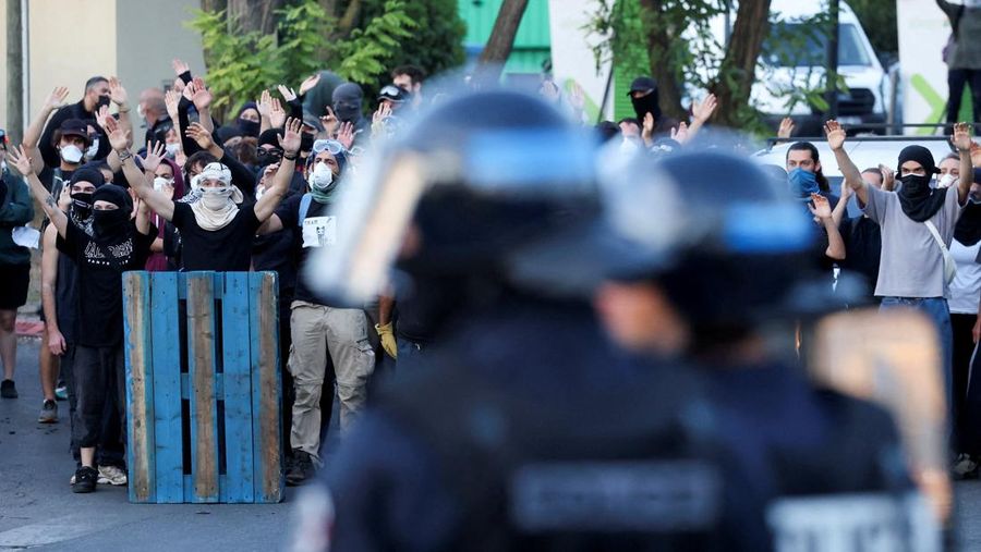 Orang-orang berdemonstrasi di bundaran untuk memblokir lalu lintas sementara petugas polisi berjaga di Pres d'Arenes di Montpellier, sebagai bagian dari gerakan protes akar rumput yang disebut 