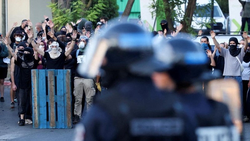 Orang-orang berdemonstrasi di bundaran untuk memblokir lalu lintas sementara petugas polisi berjaga di Pres d'Arenes di Montpellier, sebagai bagian dari gerakan protes akar rumput yang disebut 