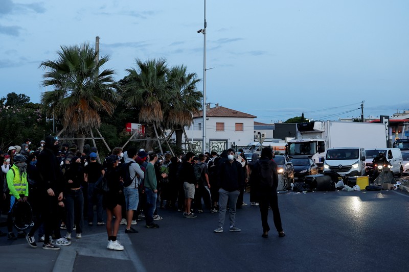 Orang-orang berdemonstrasi di bundaran untuk memblokir lalu lintas sementara petugas polisi berjaga di Pres d'Arenes di Montpellier, sebagai bagian dari gerakan protes akar rumput yang disebut Orang-orang berdemonstrasi di bundaran untuk memblokir lalu lintas sementara petugas polisi berjaga di Pres d'Arenes di Montpellier, sebagai bagian dari gerakan protes akar rumput yang disebut
