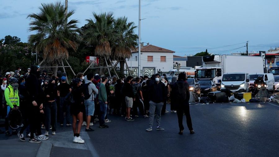 Orang-orang berdemonstrasi di bundaran untuk memblokir lalu lintas sementara petugas polisi berjaga di Pres d'Arenes di Montpellier, sebagai bagian dari gerakan protes akar rumput yang disebut 