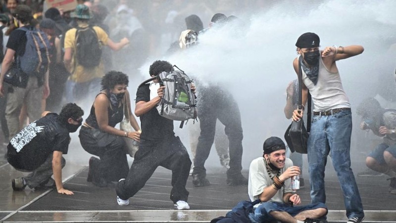Orang-orang berdemonstrasi di bundaran untuk memblokir lalu lintas sementara petugas polisi berjaga di Pres d'Arenes di Montpellier, sebagai bagian dari gerakan protes akar rumput yang disebut 