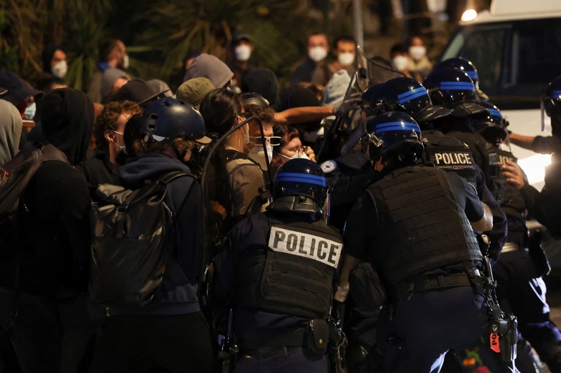 Orang-orang berdemonstrasi di bundaran untuk memblokir lalu lintas sementara petugas polisi berjaga di Pres d'Arenes di Montpellier, sebagai bagian dari gerakan protes akar rumput yang disebut 