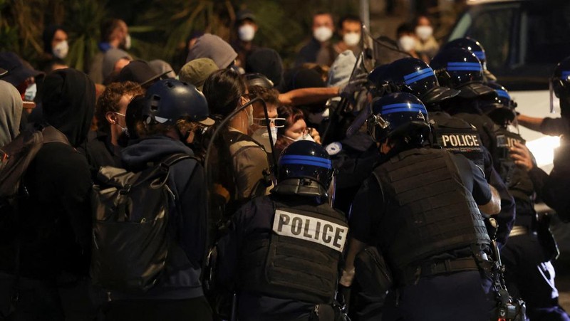 Orang-orang berdemonstrasi di bundaran untuk memblokir lalu lintas sementara petugas polisi berjaga di Pres d'Arenes di Montpellier, sebagai bagian dari gerakan protes akar rumput yang disebut 