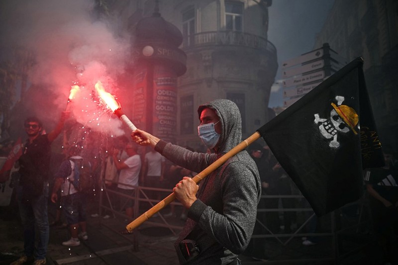 Orang-orang berdemonstrasi di bundaran untuk memblokir lalu lintas sementara petugas polisi berjaga di Pres d'Arenes di Montpellier, sebagai bagian dari gerakan protes akar rumput yang disebut 