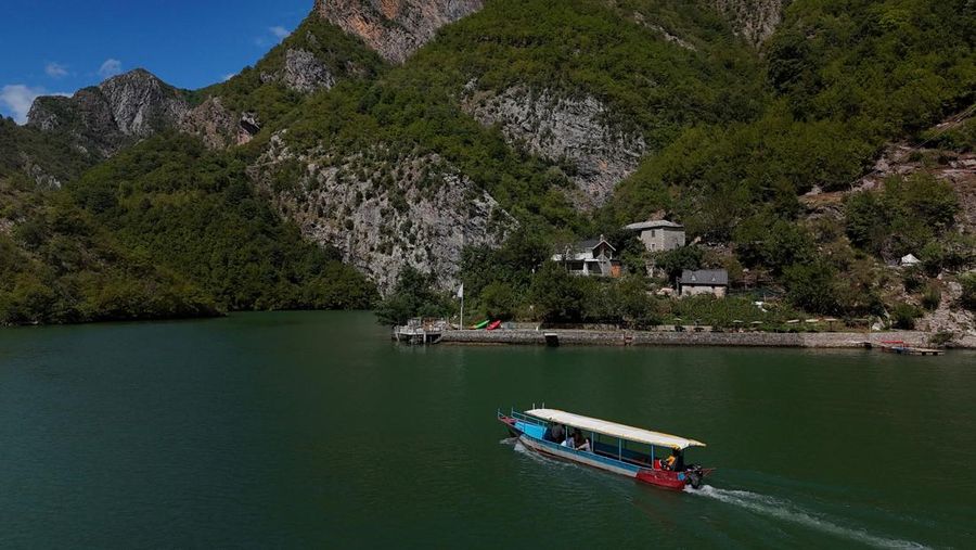A drone view shows a boat carrying tourists near the stone house of Marjana Koceku, 24, a newly elected MP, transformed into an agritourism guesthouse in a remote area at Koman lake near Shkodra, Albania, August 31, 2025. REUTERS/Florion Goga