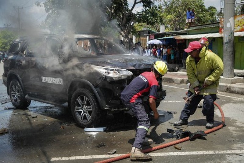A firefighter extinguishes a blaze set alight by university students protesting the parliaments plan to buy 65 SUVs for lawmakers in Dili, East Timor, on September 16, 2025. East Timor police fired tear gas on September 16 at protesters railing for the second day against a plan to buy new official cars for lawmakers, which became the latest flashpoint in one of the poorest nations in Southeast Asia. (Photo by VALENTINO DARIELL DE SOUSA / AFP)