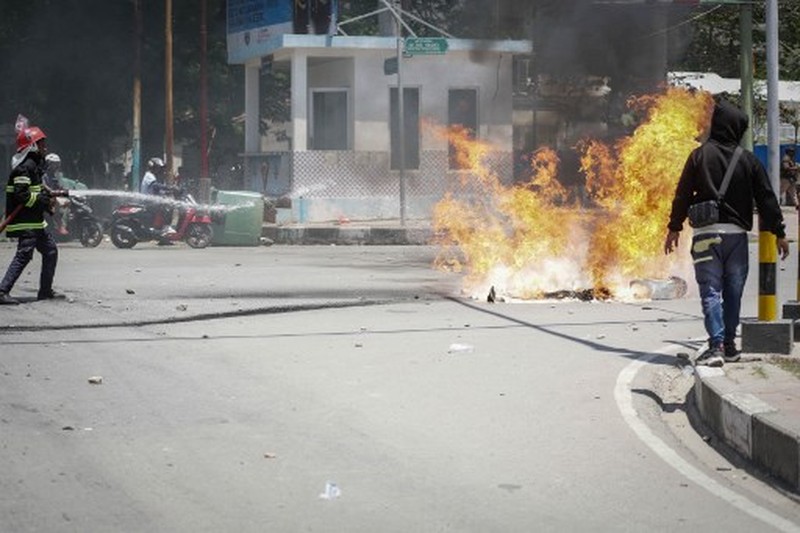 A firefighter extinguishes a blaze set alight by university students protesting the parliaments plan to buy 65 SUVs for lawmakers in Dili, East Timor, on September 16, 2025. East Timor police fired tear gas on September 16 at protesters railing for the second day against a plan to buy new official cars for lawmakers, which became the latest flashpoint in one of the poorest nations in Southeast Asia. (Photo by VALENTINO DARIELL DE SOUSA / AFP)