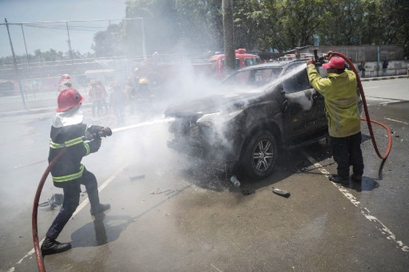 A firefighter extinguishes a blaze set alight by university students protesting the parliaments plan to buy 65 SUVs for lawmakers in Dili, East Timor, on September 16, 2025. East Timor police fired tear gas on September 16 at protesters railing for the second day against a plan to buy new official cars for lawmakers, which became the latest flashpoint in one of the poorest nations in Southeast Asia. (Photo by VALENTINO DARIELL DE SOUSA / AFP)