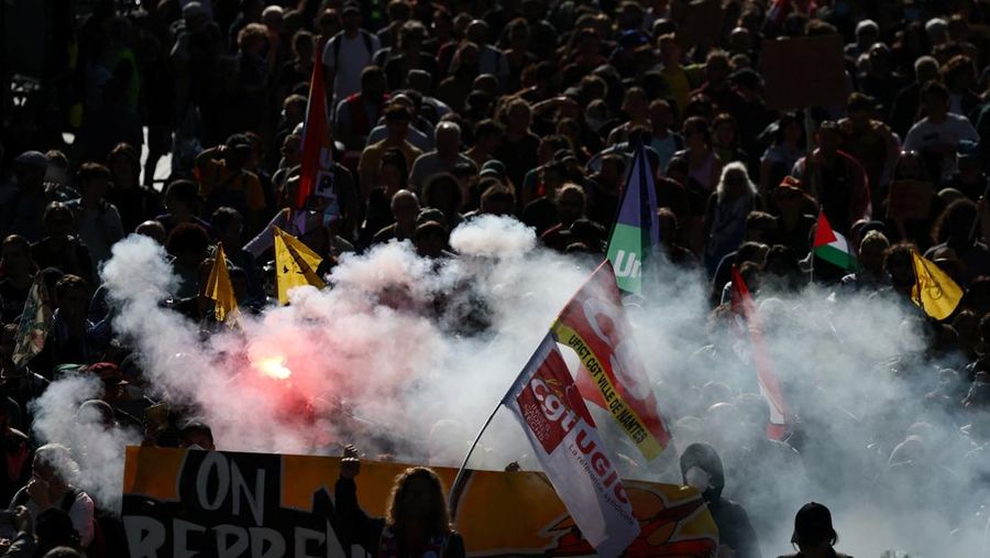 Para pengunjuk rasa membawa suar dan bendera serikat buruh selama demonstrasi di Nantes sebagai bagian dari aksi mogok dan protes nasional terhadap pemerintah dan pemotongan anggaran berikutnya, bersama para pendukung gerakan