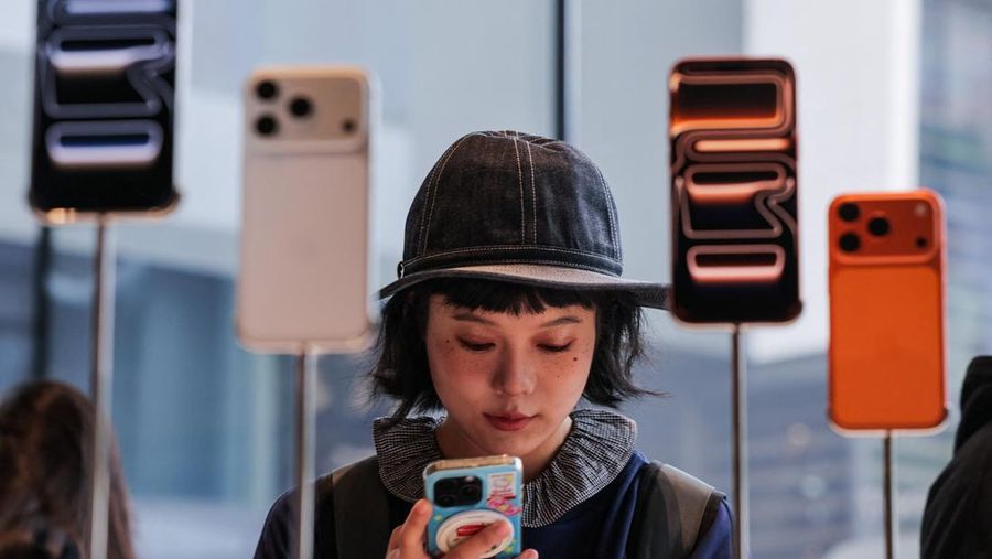 Seorang wanita menggunakan ponsel pintarnya di dalam toko Apple di kawasan Sanlitun, Beijing, saat ponsel pintar seri iPhone 17 baru mulai dijual di Beijing, Tiongkok, 19 September 2025. REUTERS/Maxim Shemetov
