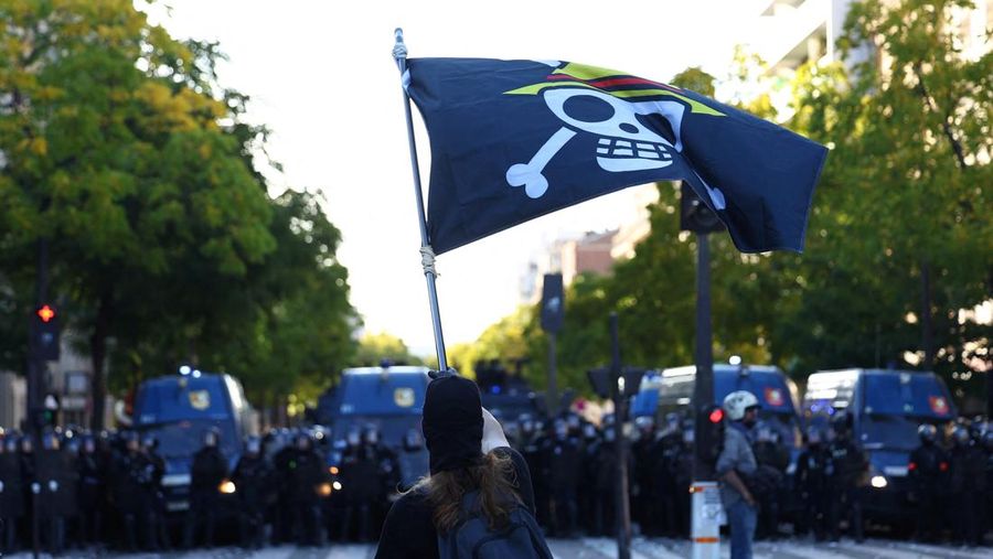 French riot police stand amid tear gas during clashes at a demonstration in Paris as part of a day of nationwide strikes and protests against the government and cuts in the next budget, with supporters of the 