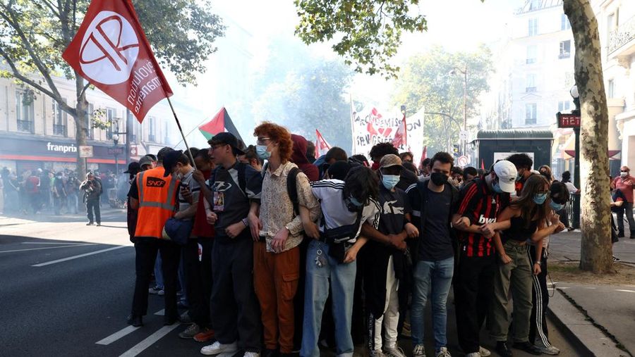 French riot police stand amid tear gas during clashes at a demonstration in Paris as part of a day of nationwide strikes and protests against the government and cuts in the next budget, with supporters of the 
