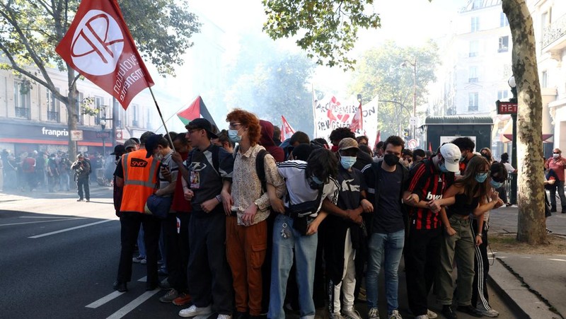 French riot police stand amid tear gas during clashes at a demonstration in Paris as part of a day of nationwide strikes and protests against the government and cuts in the next budget, with supporters of the 