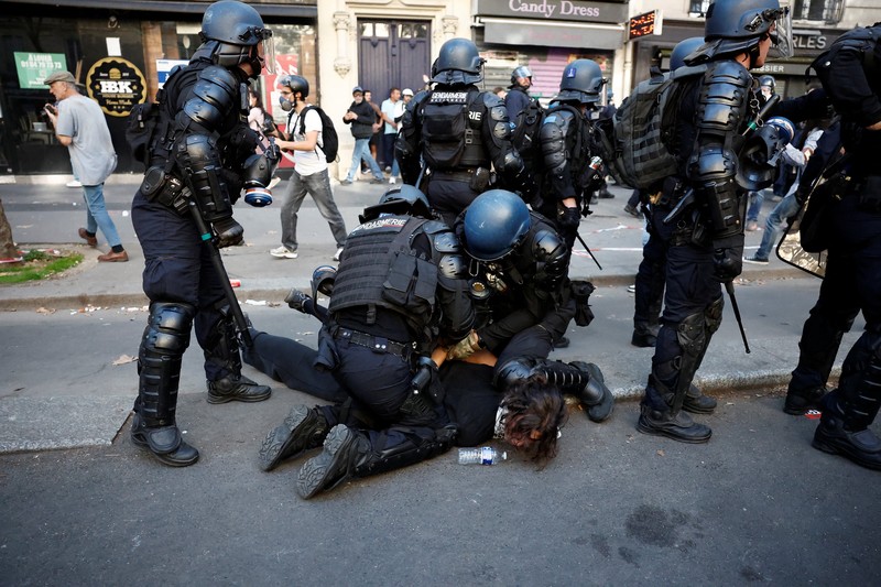 French riot police stand amid tear gas during clashes at a demonstration in Paris as part of a day of nationwide strikes and protests against the government and cuts in the next budget, with supporters of the 