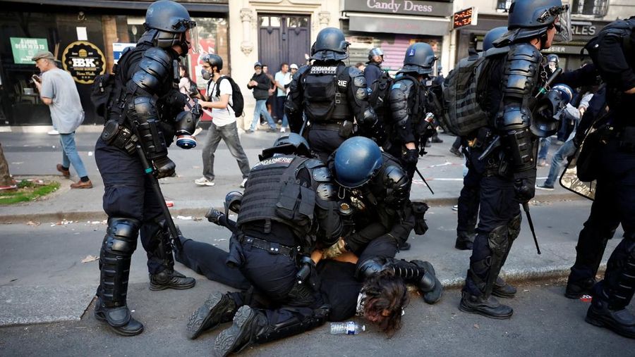 French riot police stand amid tear gas during clashes at a demonstration in Paris as part of a day of nationwide strikes and protests against the government and cuts in the next budget, with supporters of the 