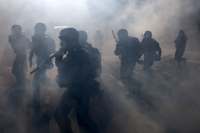 French riot police stand amid tear gas during clashes at a demonstration in Paris as part of a day of nationwide strikes and protests against the government and cuts in the next budget, with supporters of the 