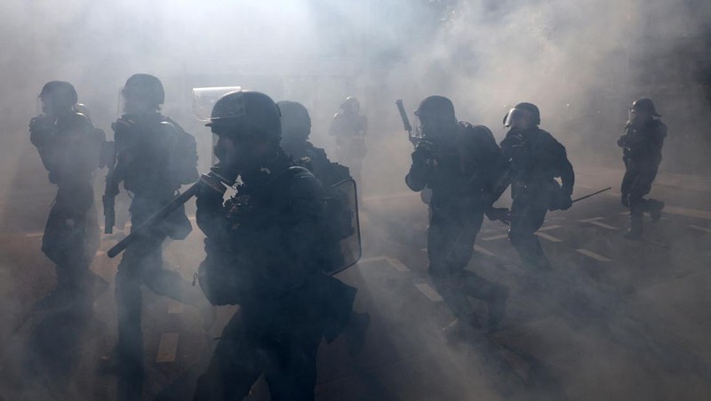 French riot police stand amid tear gas during clashes at a demonstration in Paris as part of a day of nationwide strikes and protests against the government and cuts in the next budget, with supporters of the 