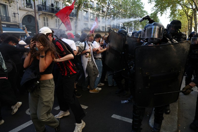French riot police stand amid tear gas during clashes at a demonstration in Paris as part of a day of nationwide strikes and protests against the government and cuts in the next budget, with supporters of the 