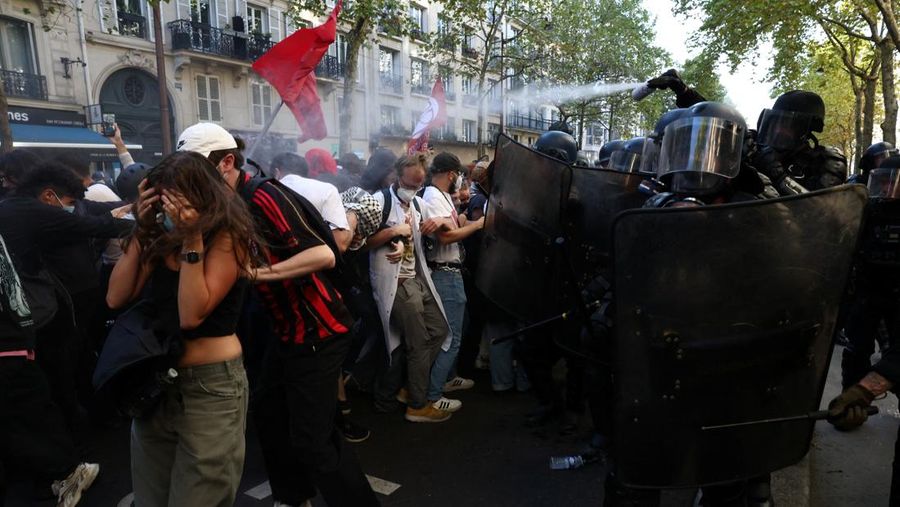 French riot police stand amid tear gas during clashes at a demonstration in Paris as part of a day of nationwide strikes and protests against the government and cuts in the next budget, with supporters of the 