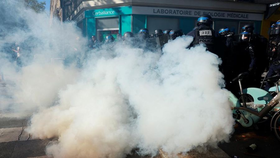 French riot police stand amid tear gas during clashes at a demonstration in Paris as part of a day of nationwide strikes and protests against the government and cuts in the next budget, with supporters of the 