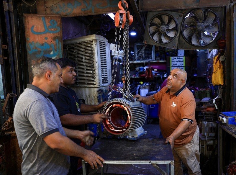 Orang-orang berjalan di sepanjang jalan tua sementara jalinan kabel listrik yang kusut dari generator yang memasok listrik ke rumah-rumah tergantung di atas gedung-gedung, di Baghdad, Irak, 10 September 2025. Orang-orang berjalan di sepanjang jalan tua sementara jalinan kabel listrik yang kusut dari generator yang memasok listrik ke rumah-rumah tergantung di atas gedung-gedung, di Baghdad, Irak, 10 September 2025. (REUTERS/Thaier Al-Sudani)
