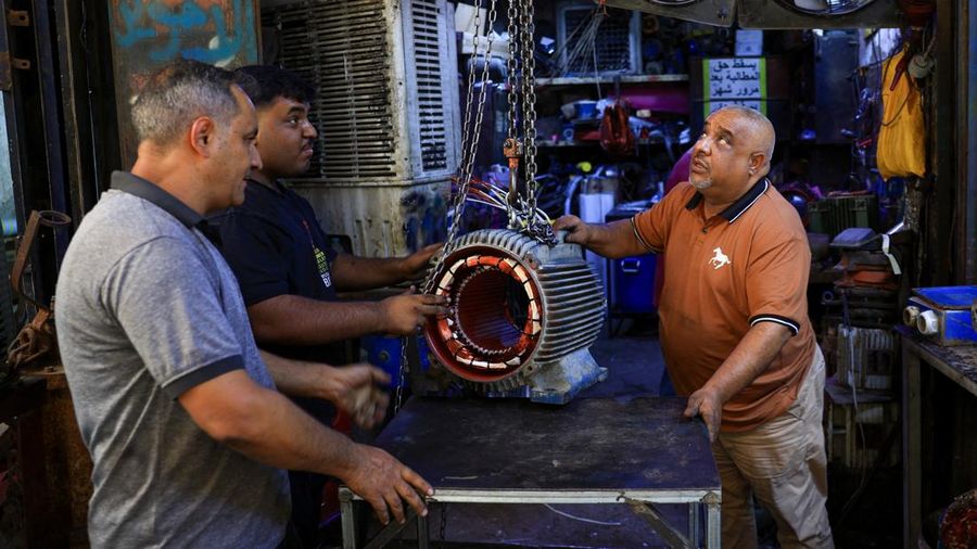Orang-orang berjalan di sepanjang jalan tua sementara jalinan kabel listrik yang kusut dari generator yang memasok listrik ke rumah-rumah tergantung di atas gedung-gedung, di Baghdad, Irak, 10 September 2025. Orang-orang berjalan di sepanjang jalan tua sementara jalinan kabel listrik yang kusut dari generator yang memasok listrik ke rumah-rumah tergantung di atas gedung-gedung, di Baghdad, Irak, 10 September 2025. (REUTERS/Thaier Al-Sudani)