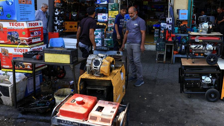 Orang-orang berjalan di sepanjang jalan tua sementara jalinan kabel listrik yang kusut dari generator yang memasok listrik ke rumah-rumah tergantung di atas gedung-gedung, di Baghdad, Irak, 10 September 2025. Orang-orang berjalan di sepanjang jalan tua sementara jalinan kabel listrik yang kusut dari generator yang memasok listrik ke rumah-rumah tergantung di atas gedung-gedung, di Baghdad, Irak, 10 September 2025. (REUTERS/Thaier Al-Sudani)