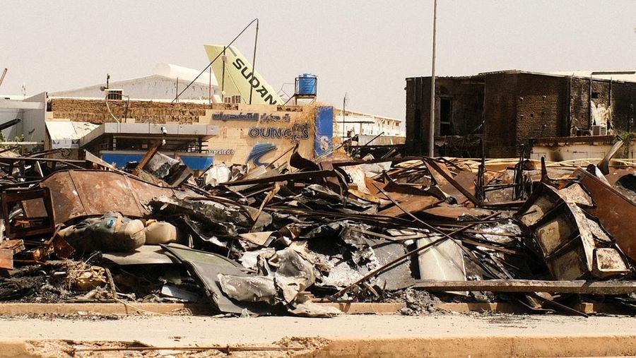 Pemandangan gedung yang terbakar dan ekor pesawat Sudan Airways di tengah puing-puing di Bandara Khartoum, setelah tentara Sudan memperdalam kendali atas Khartoum dari Pasukan Dukungan Cepat (RSF), di Khartoum, Sudan, 26 April 2025. REUTERS/El Tayeb Siddig/File Photo)