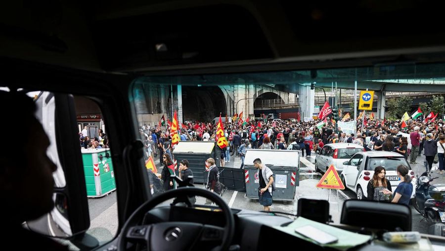 Para demonstran membawa suar asap, sementara para pekerja pelabuhan ikut serta dalam aksi mogok di dekat pelabuhan Genoa sebagai bagian dari protes nasional 