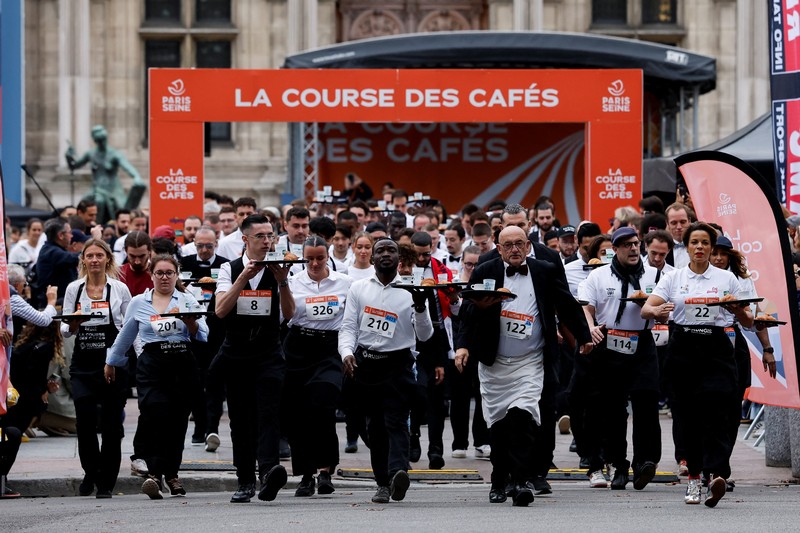 Pelayan membawa nampan berisi secangkir kopi, croissant, dan segelas air ikut serta dalam Cafe Race di Paris, Prancis, 21 September 2025. (REUTERS/Stephanie Lecocq)
