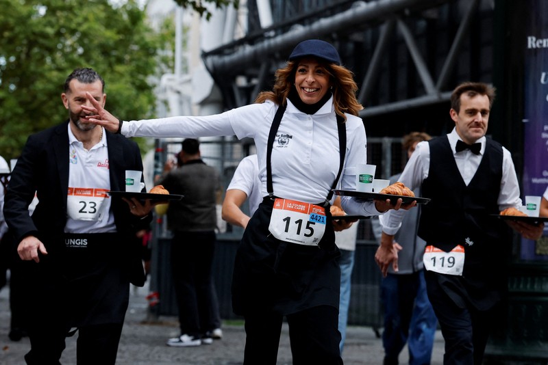 Pelayan membawa nampan berisi secangkir kopi, croissant, dan segelas air ikut serta dalam Cafe Race di Paris, Prancis, 21 September 2025. (REUTERS/Stephanie Lecocq)