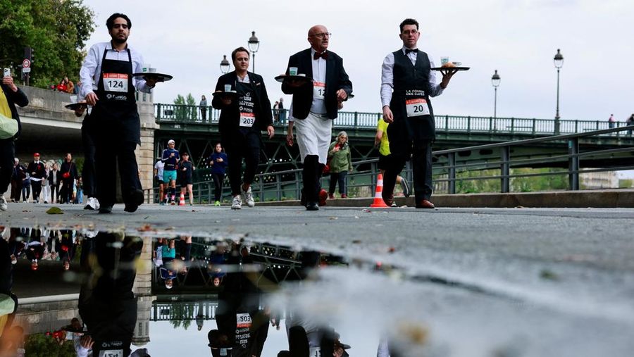 Pelayan membawa nampan berisi secangkir kopi, croissant, dan segelas air ikut serta dalam Cafe Race di Paris, Prancis, 21 September 2025. (REUTERS/Stephanie Lecocq)