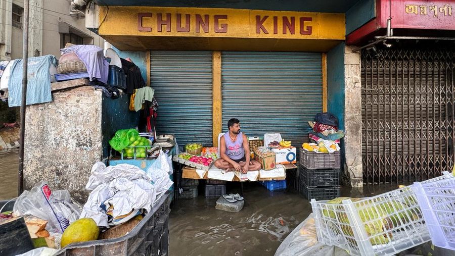 Orang-orang berjalan melalui jalan yang tergenang air setelah hujan deras di Kolkata, India, 24 September 2025. (REUTERS/Sahiba Chawdhary)