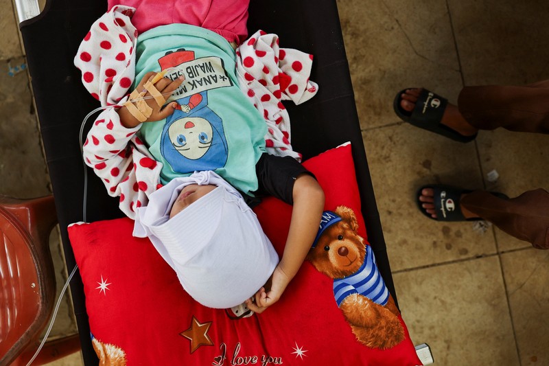 Muhammad Setiawan Pratama, 11, seorang siswa sekolah dasar menerima perawatan keracunan makanan setelah makan makanan sekolah gratis yang disponsori pemerintah, di sebuah klinik darurat di dalam aula kabupaten di Bandung, provinsi Jawa Barat, Indonesia, 25 September 2025. Muhammad Setiawan Pratama, 11, seorang siswa sekolah dasar menerima perawatan keracunan makanan setelah makan makanan sekolah gratis yang disponsori pemerintah, di sebuah klinik darurat di dalam aula kabupaten di Bandung, provinsi Jawa Barat, Indonesia, 25 September 2025. (REUTERS/Willy Kurniawan)