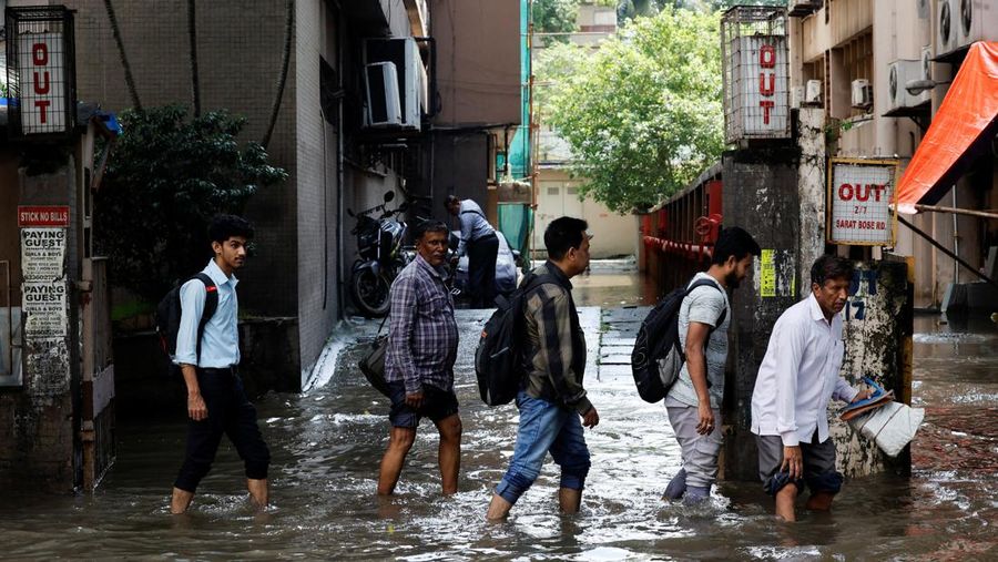 Orang-orang berjalan melalui jalan yang tergenang air setelah hujan deras di Kolkata, India, 24 September 2025. (REUTERS/Sahiba Chawdhary)