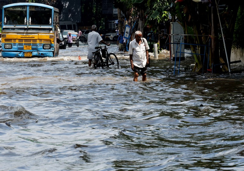 Orang-orang berjalan melalui jalan yang tergenang air setelah hujan deras di Kolkata, India, 24 September 2025. (REUTERS/Sahiba Chawdhary)