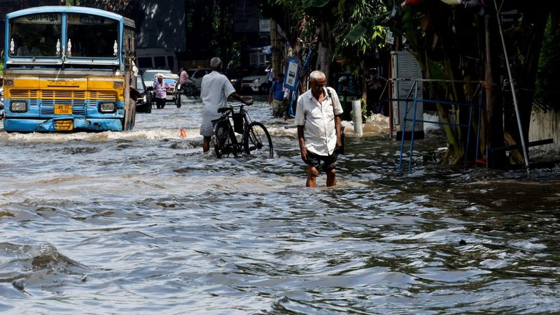 Orang-orang berjalan melalui jalan yang tergenang air setelah hujan deras di Kolkata, India, 24 September 2025. (REUTERS/Sahiba Chawdhary)
