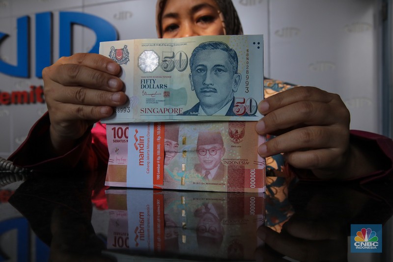 Petugas menjunjukkan mata uang Dolar Singapura di VIP Money Changer, Jakarta, Kamis (25/9/2025). Petugas menjunjukkan mata uang Dolar Singapura di VIP Money Changer, Jakarta, Kamis (25/9/2025). (CNBC Indonesia/Faisal Rahman)