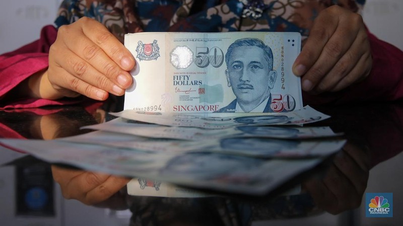Petugas menjunjukkan mata uang Dolar Singapura di VIP Money Changer, Jakarta, Kamis (25/9/2025). (CNBC Indonesia/Faisal Rahman)